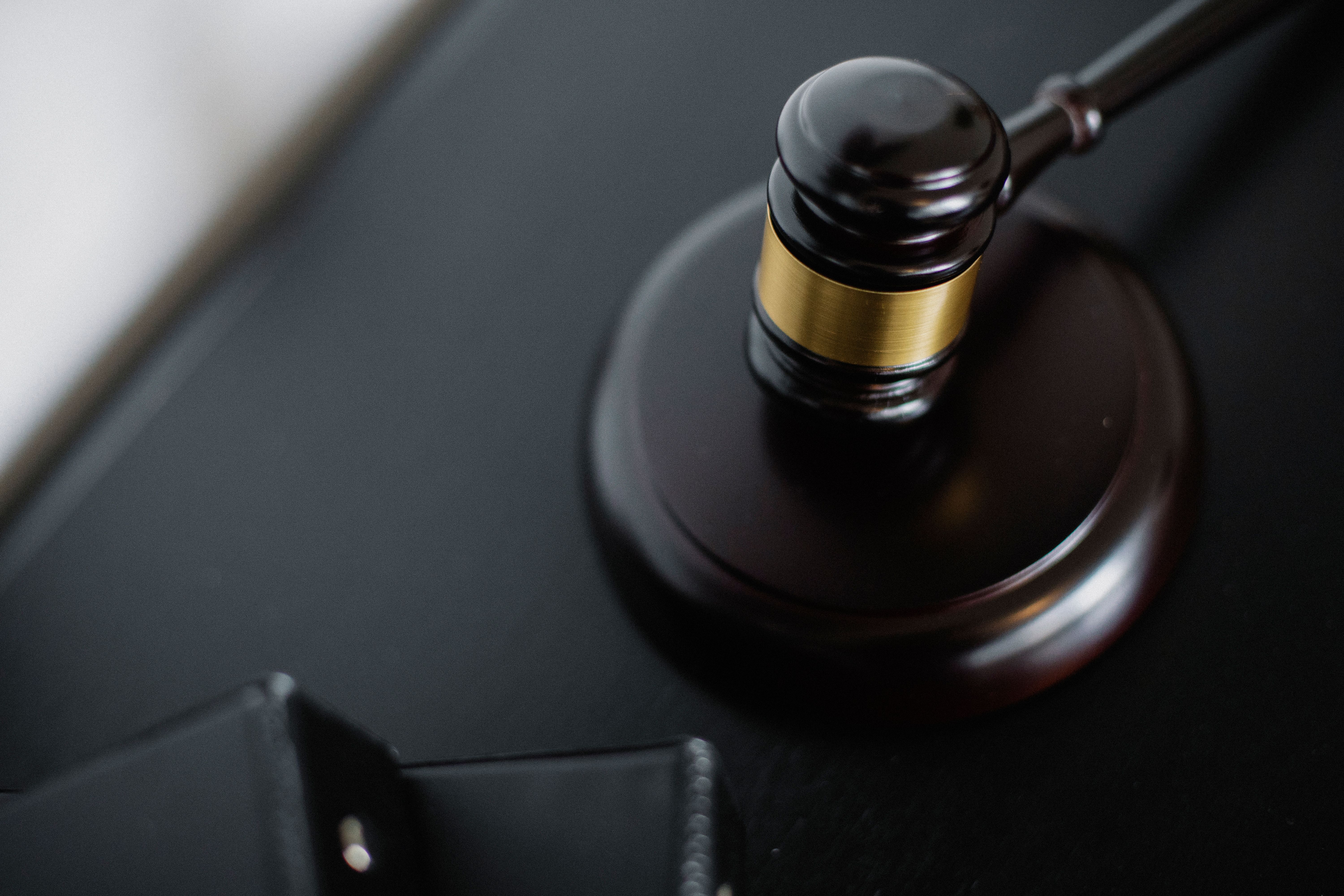 A wooden gavel beside legal folders, representing court proceedings and justice.
