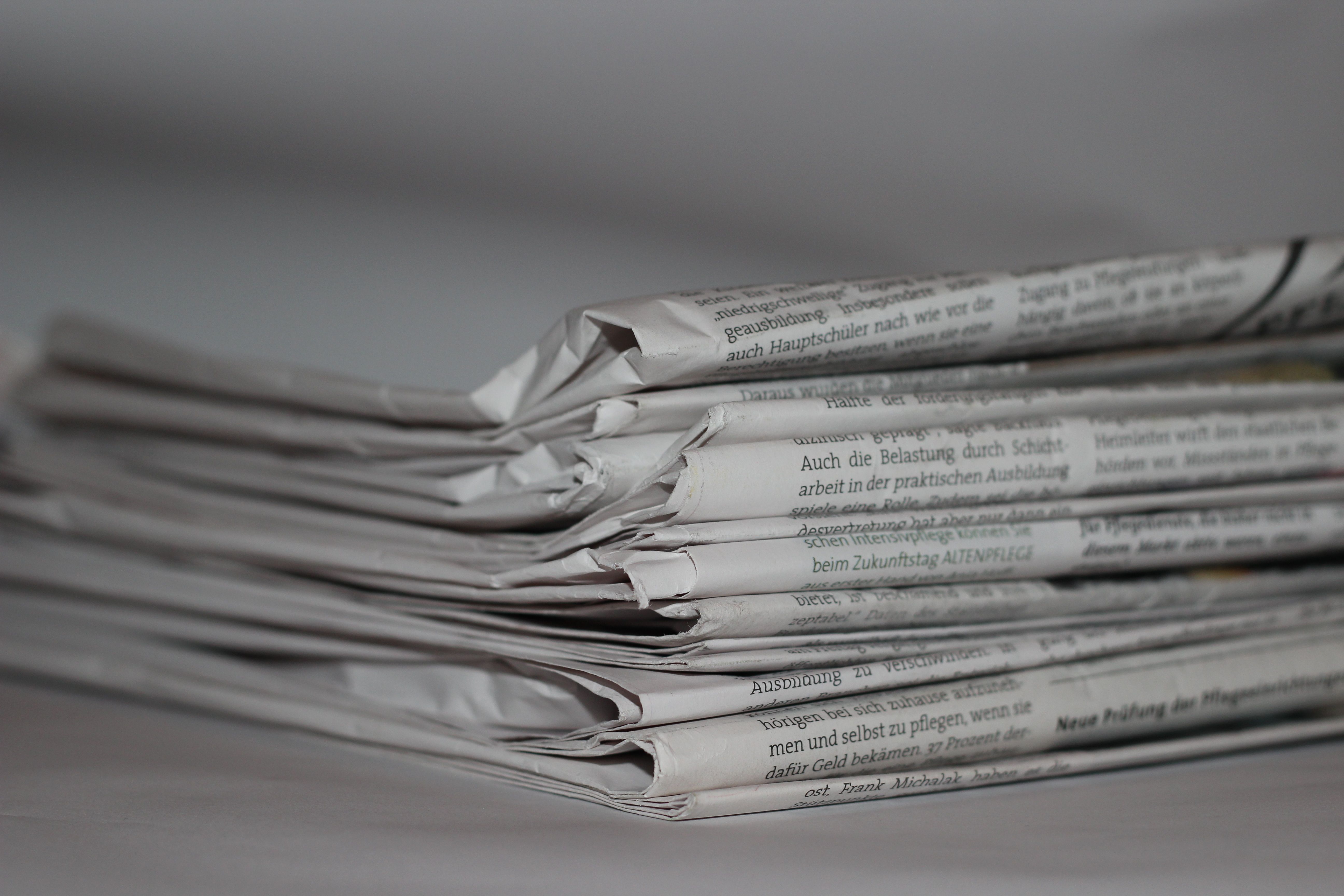 Stack of folded newspapers representing independent media and print journalism