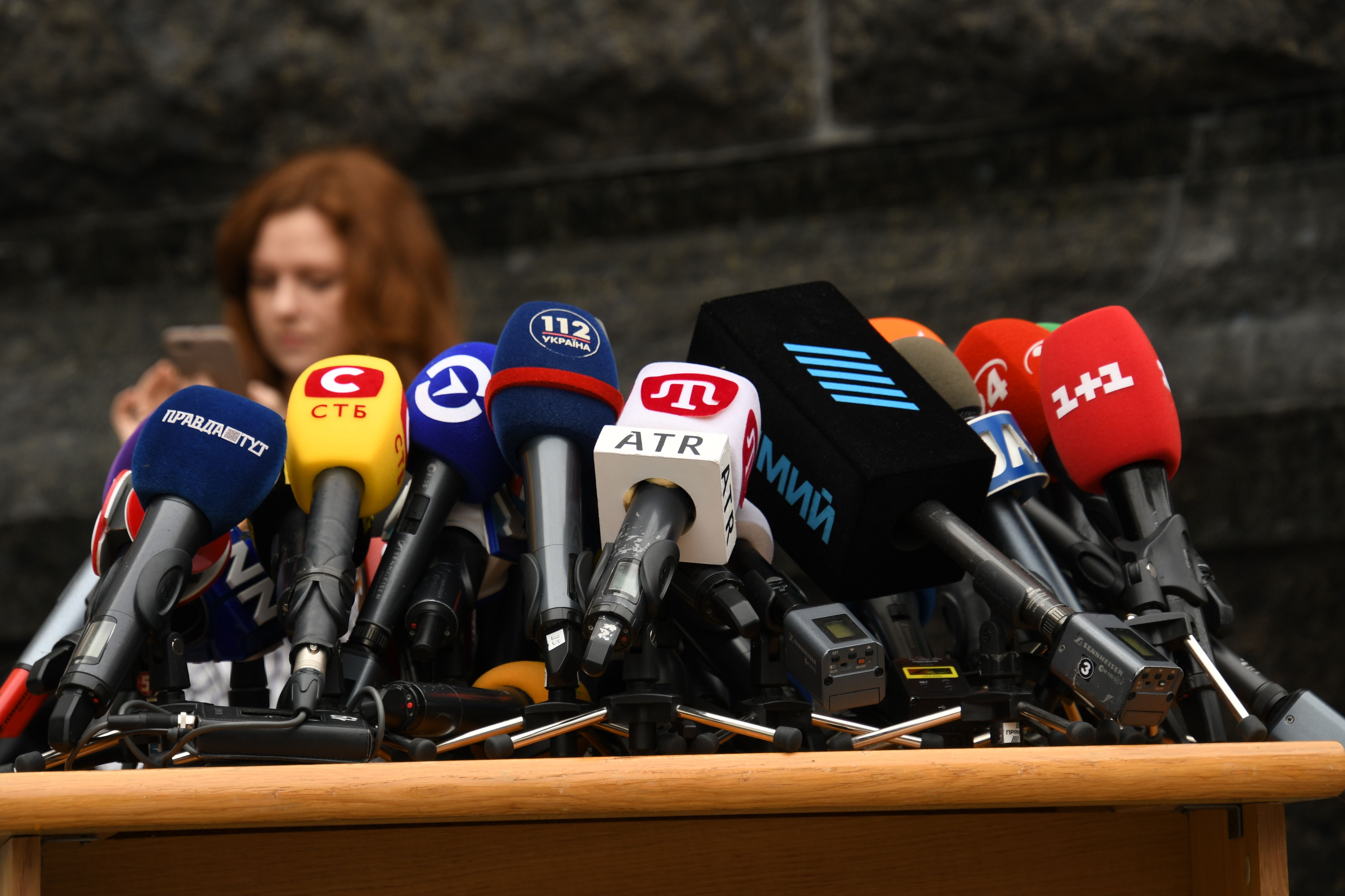 Multiple microphones set up at a press conference representing media access